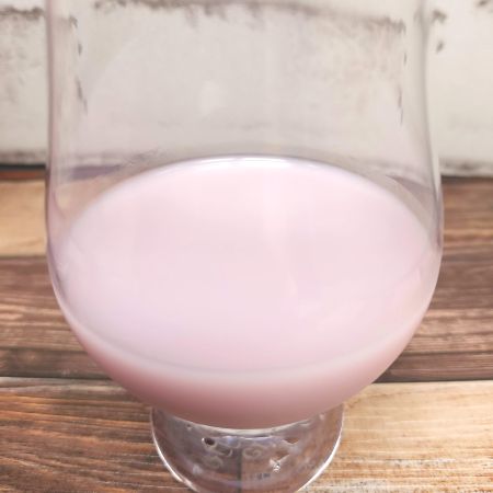 「サンガリア とろけるおいしさ ラムレーズン&ミルク」をテイスティンググラスに注いだ画像